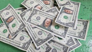Several imitation U.S. one-dollar bills with a different face and Russian text are scattered on a green surface.