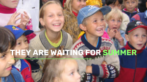 A group of children wearing colorful sweaters and hats smile and look ahead; overlaid text reads, "They are waiting for summer.